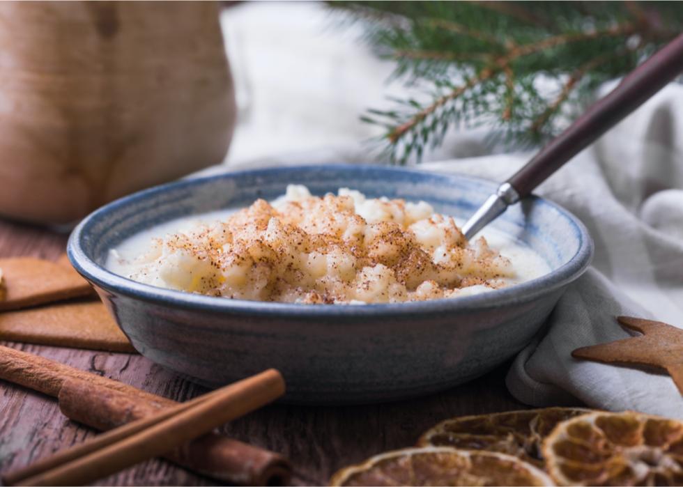 A bowl of rice pudding with a Christmas tree branch in the background.