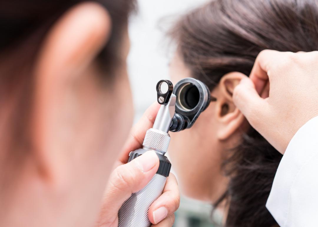 Doctor examining patient’s ear with otoscope.