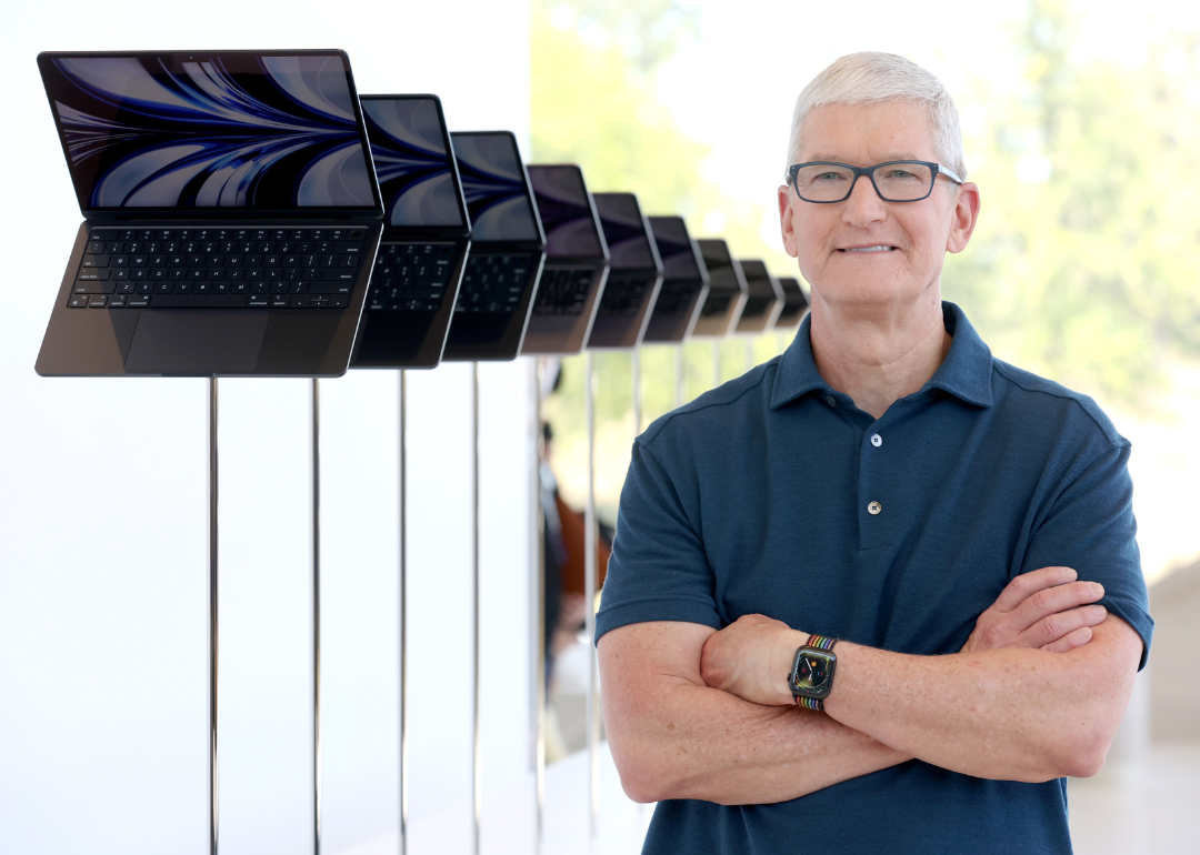 Tim Cook stands next to a display of laptops during the WWDC22.