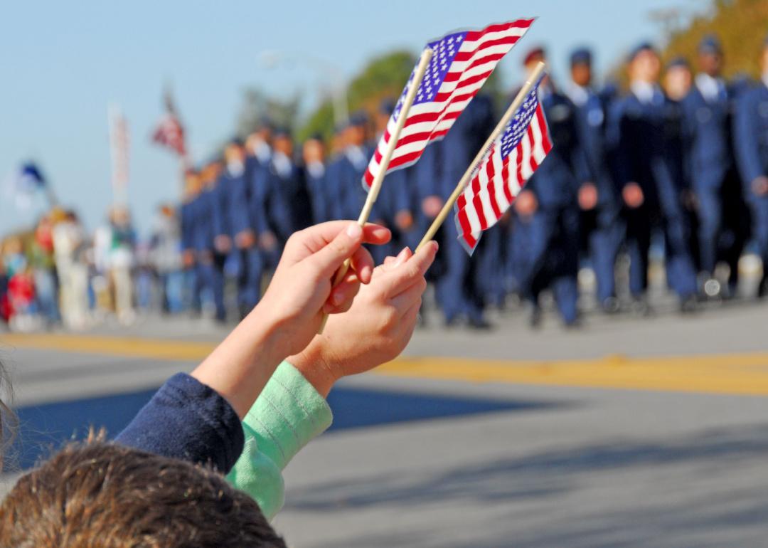 Hands waving American flags at a parade.