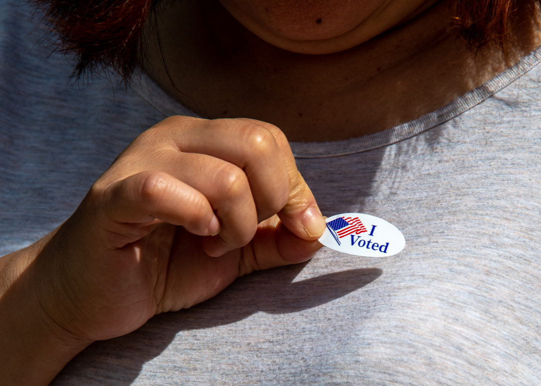 Female voter places “I voted” sticker on shirt