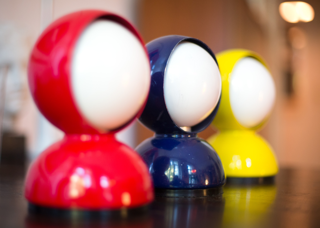 Three ‘Eclisse’ table lamps in red, blue, and yellow.
