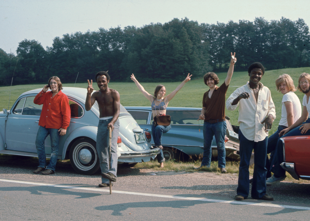 People on the way to Woodstock by parked cars on the side of the road.