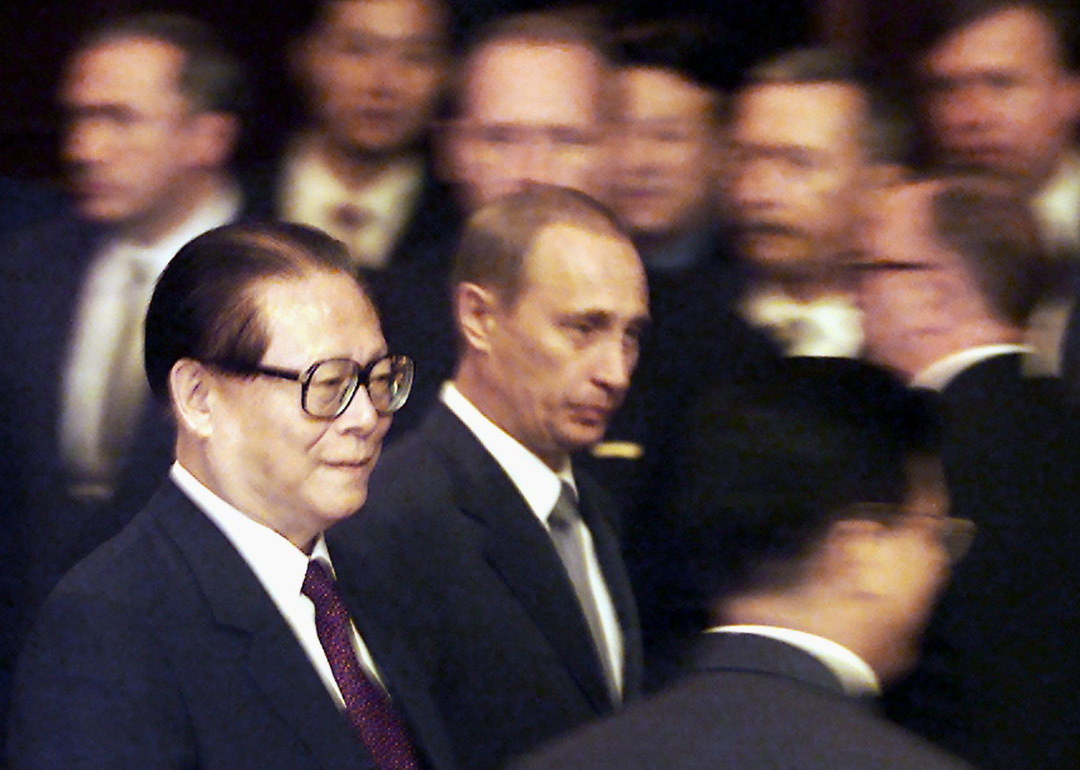 Jiang Zemin and Vladimir Putin walking through crowd of officials