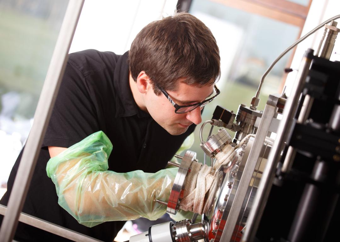 Scientist inserts hand laser deposition chamber.