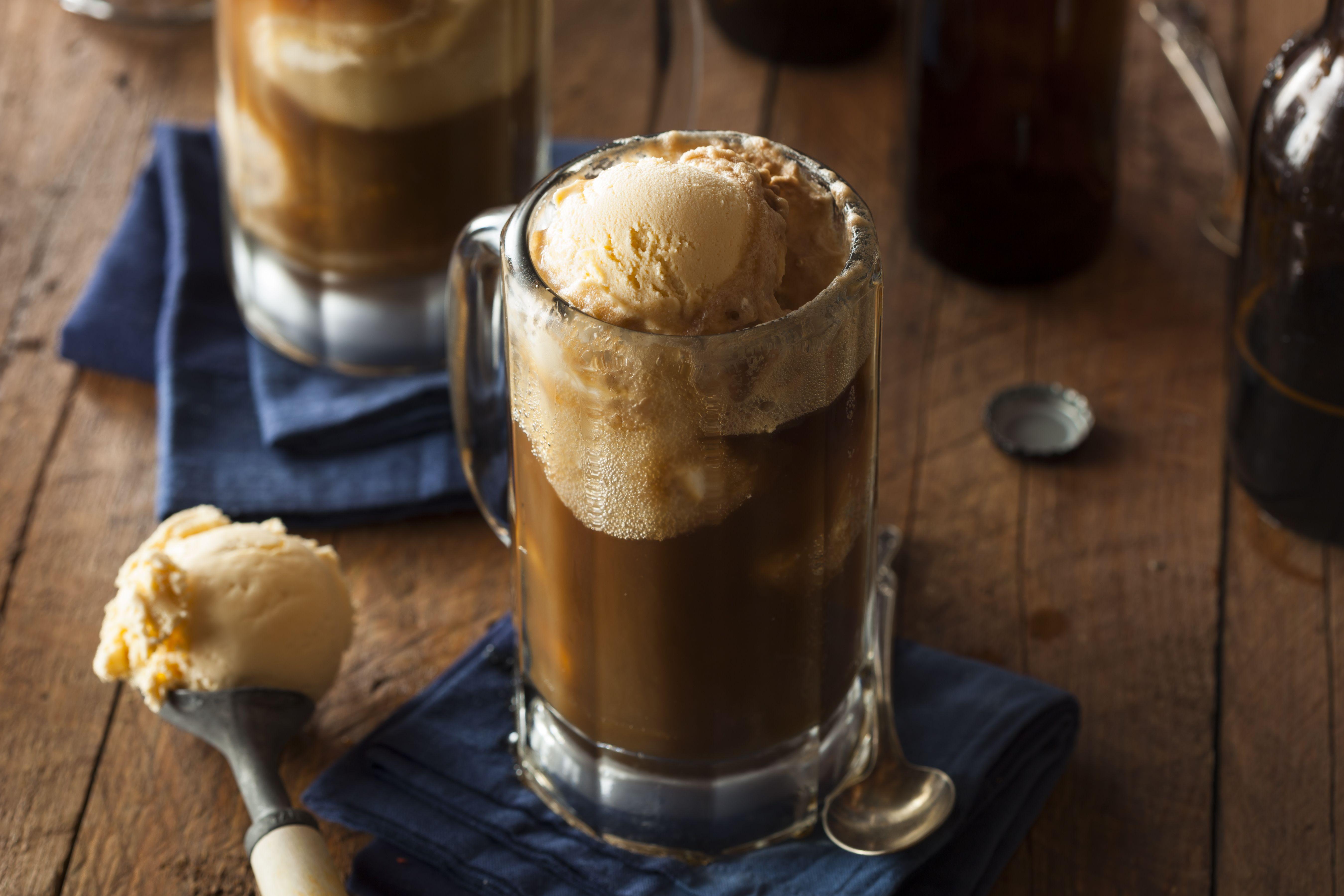Two root beer floats with scoop full of vanilla ice cream next to them.