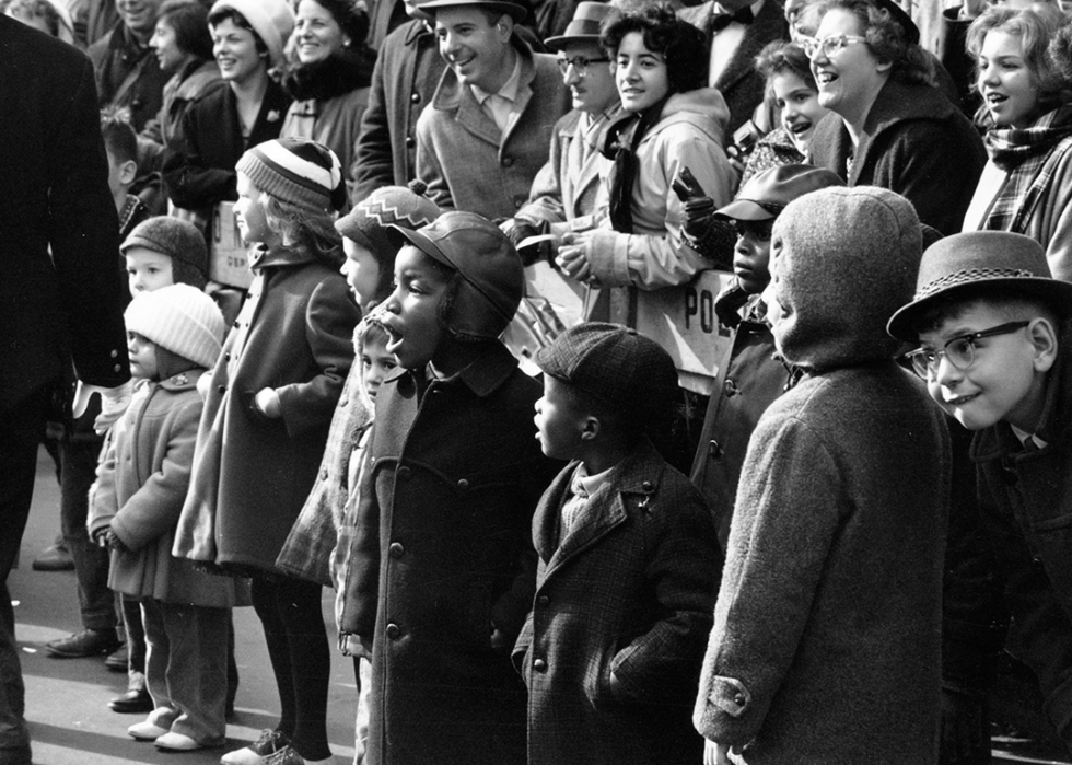 A crowd of children stand along police barricade to watch the parade.