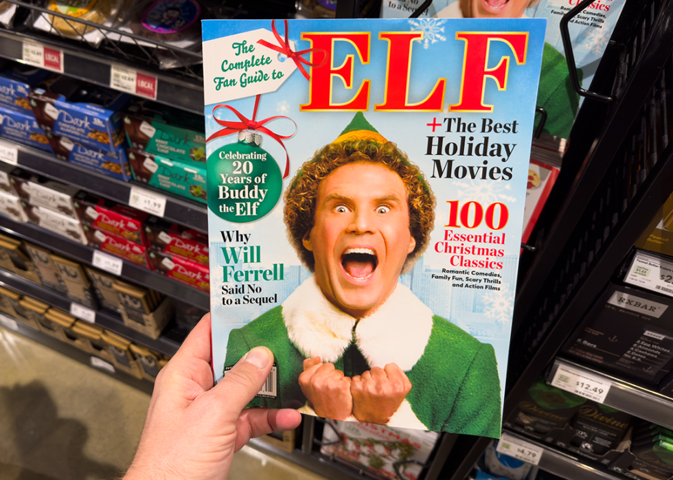 Hand holding a book titled The Complete Fan Guide to Elf with a photo of Will Ferrell.