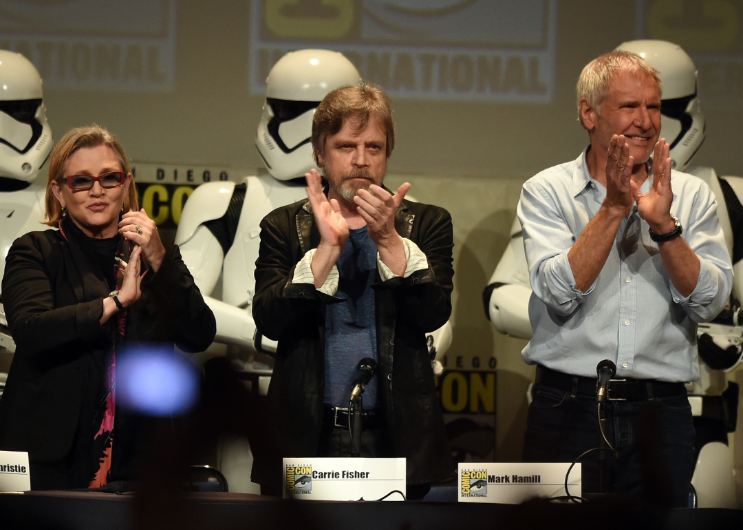Carrie Fisher, Mark Hamill and Harrison Ford applaud onstage at ComicCon