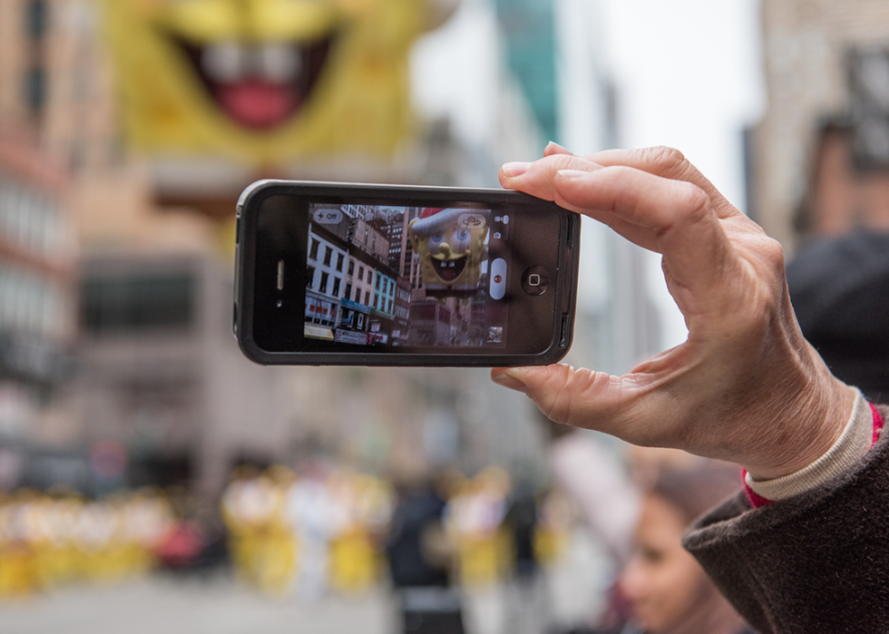 A spectator records the Spongebob Squarepants balloon on a smartphone.