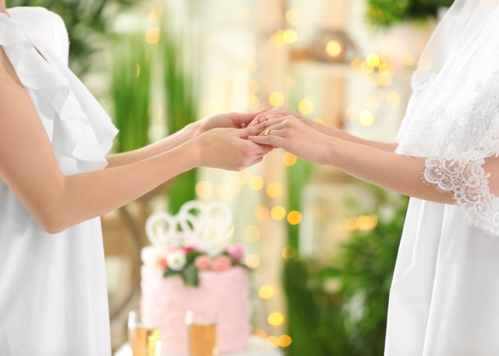Closeup of two women holding hands during marriage ceremony