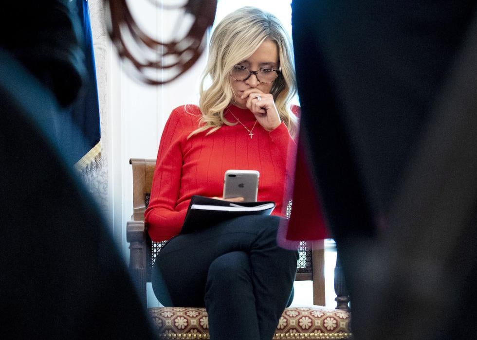 White House Press Secretary Kayleigh McEnany looks at her smart phone as U.S. President Donald Trump hosts Texas Governor Greg Abbott during the novel coronavirus pandemic in the Oval Office at the White House May 07, 2020 in Washington, DC.