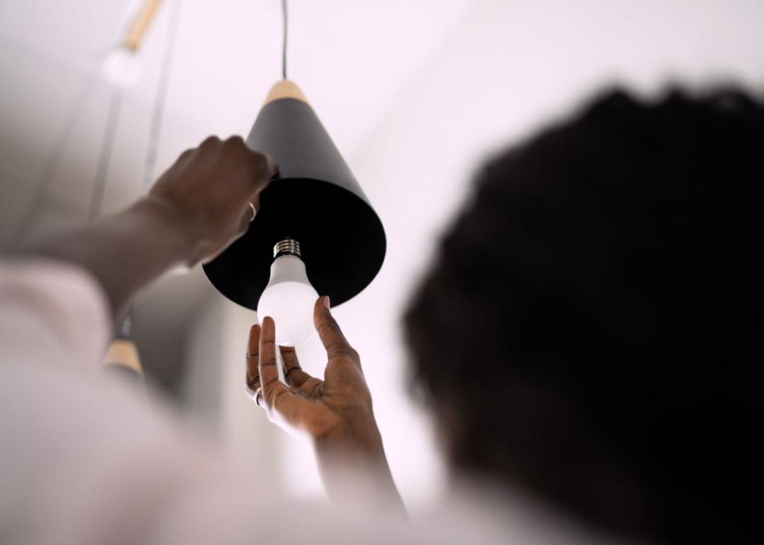Woman changing lightbulb to LED