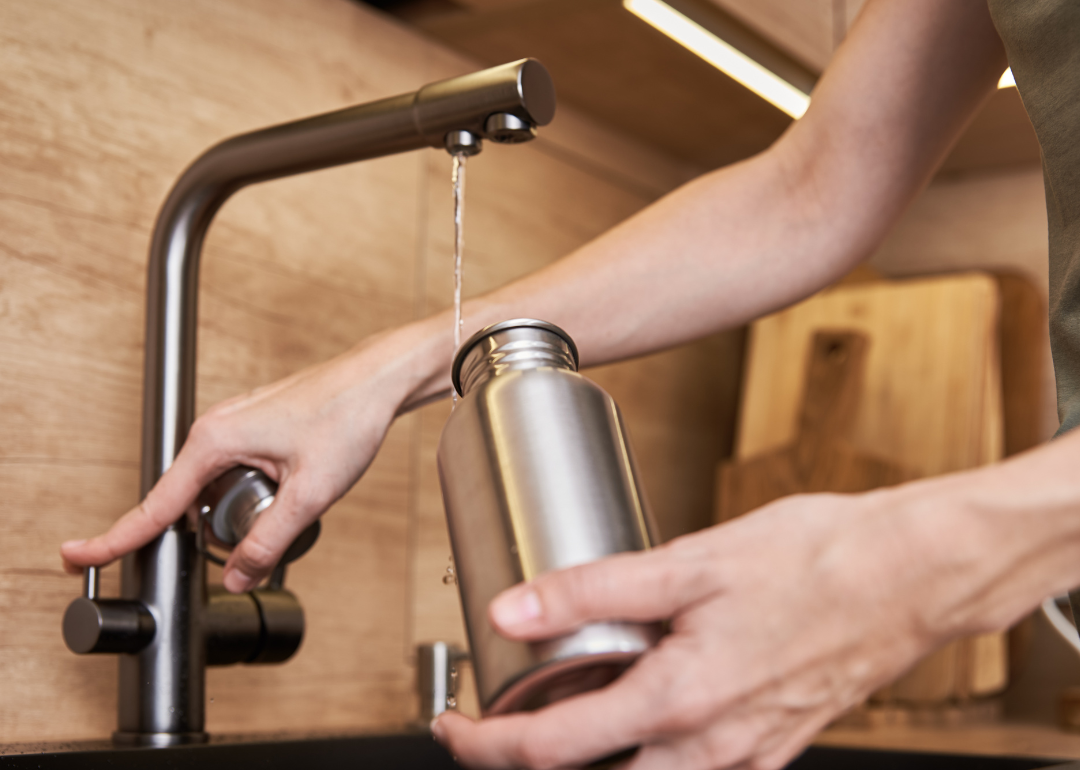 Person filling a metal water bottle with filtered faucet water
