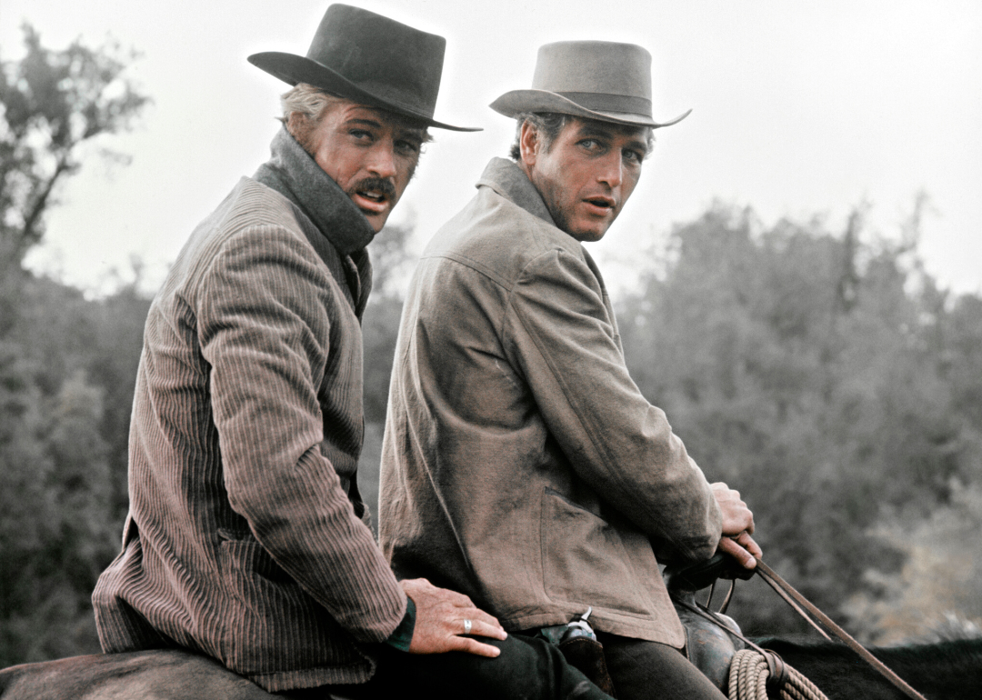 Robert Redford and Paul Newman ride a horse together.