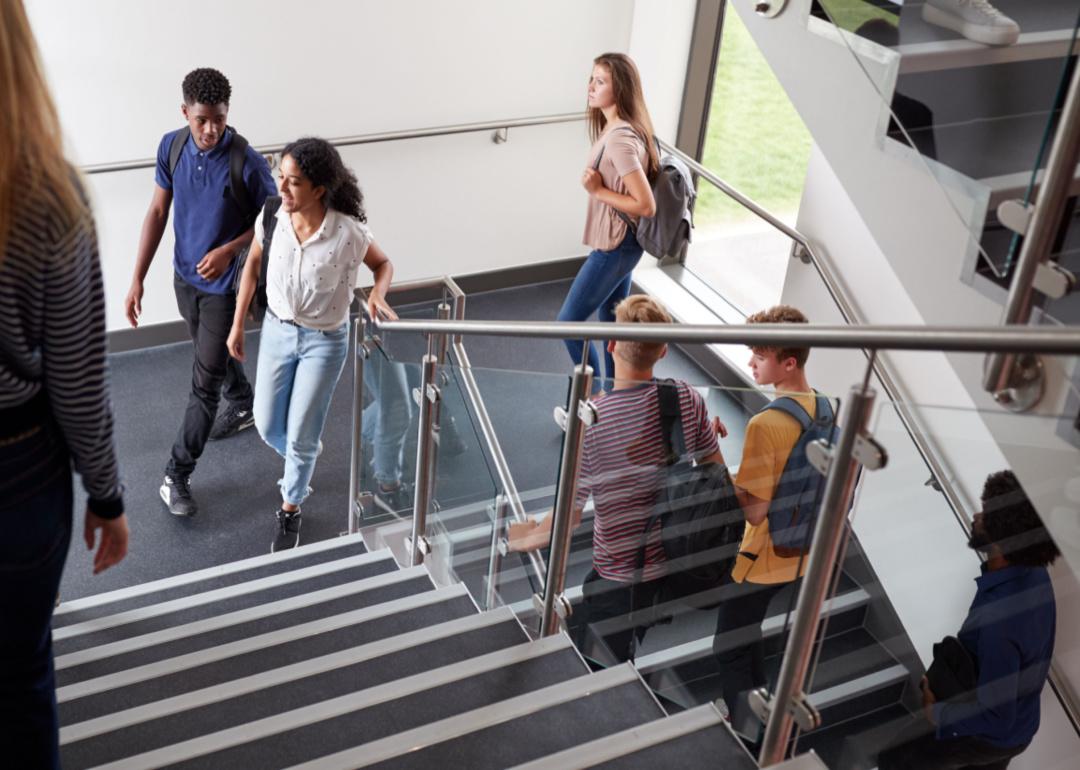 A group of teen students ascend a staircase at school