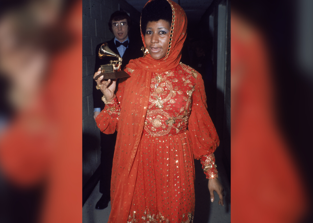 Aretha Franklin backstage wearing an embroidered gown and holding a Grammy Award.