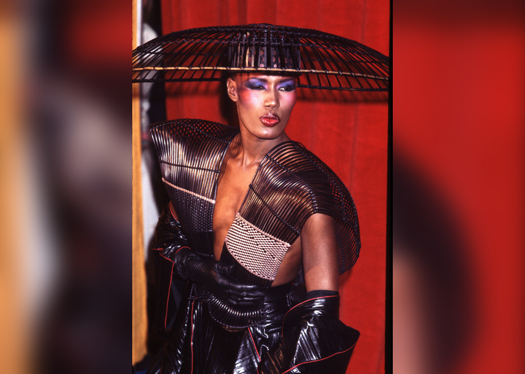 Grace Jones posing in a wicker basket hat and outfit.