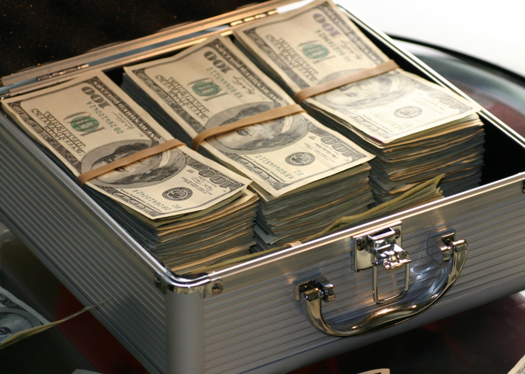 A silver briefcase filled with stacks of one hundred dollars bills.
