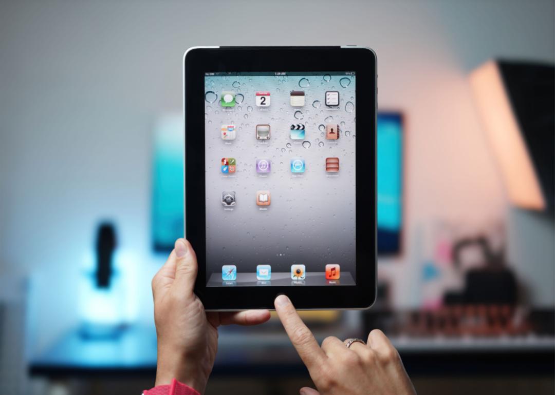 Hands holding an original iPad from 2010.