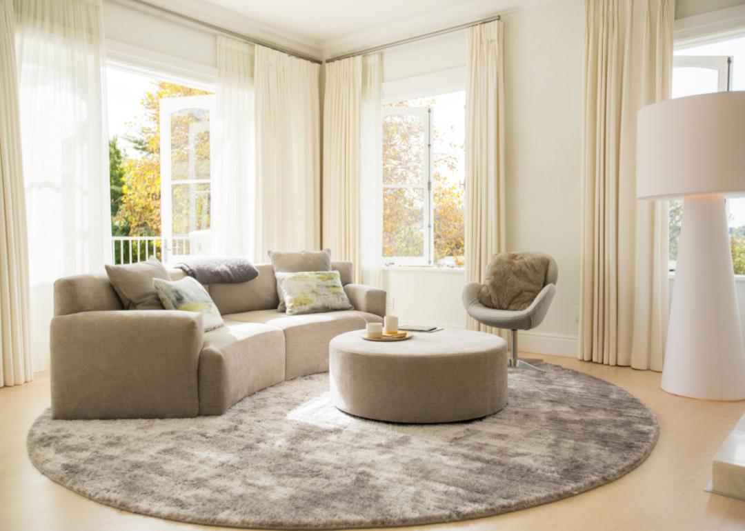 Living room with beige, curved sofa and round rug.