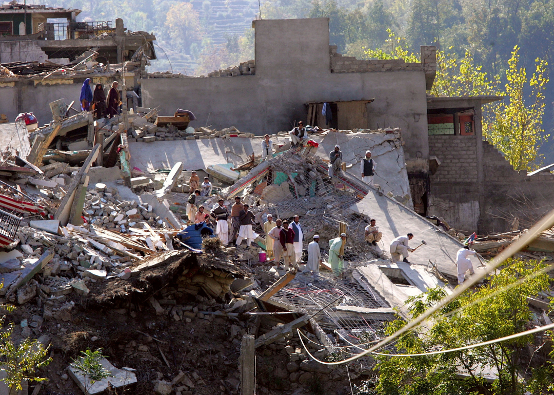 Villagers stand atop the ruins of their homes in Kot Qala, Pakistan.