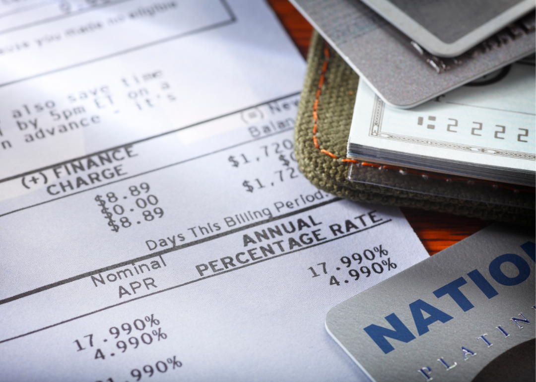 A credit card and checkbook lie atop a credit card bill.