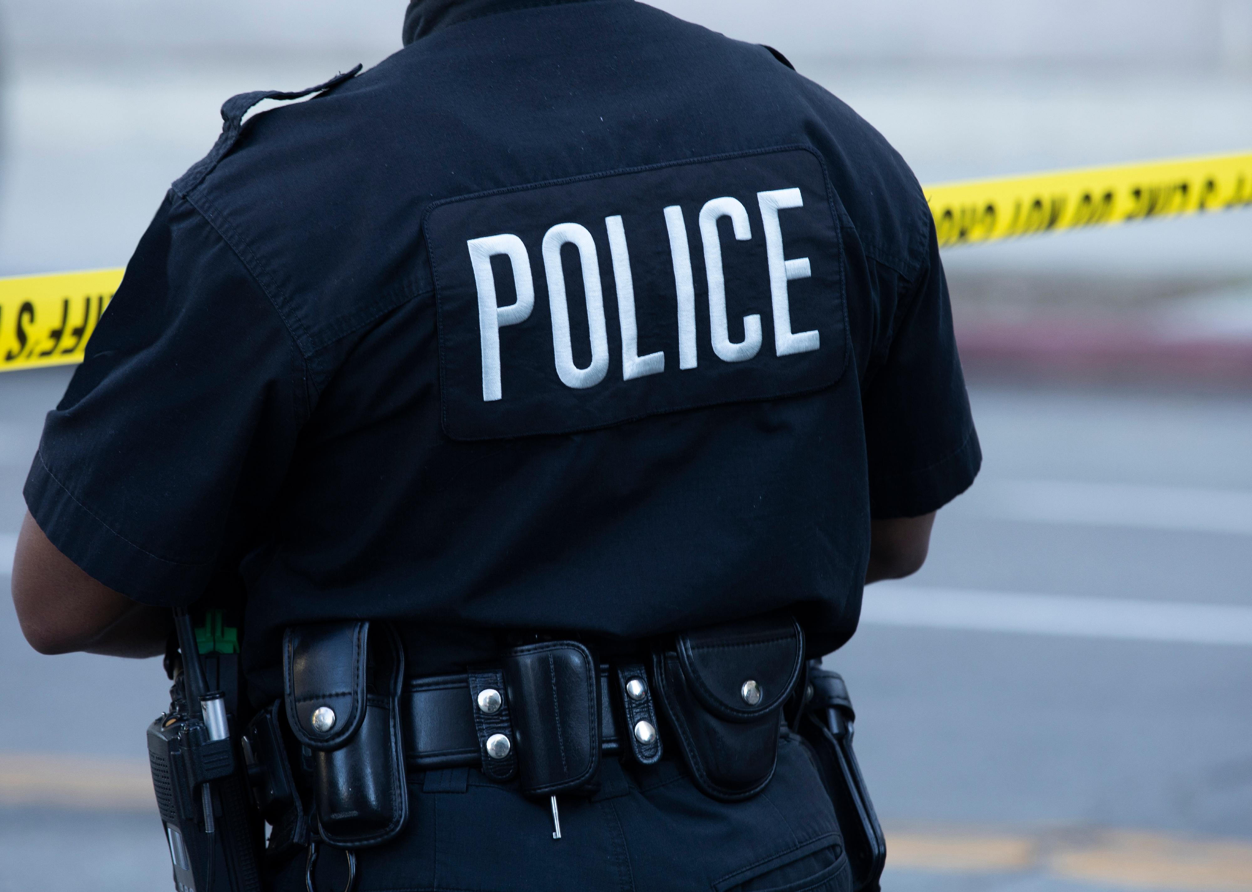 Detailed view of police uniform and tape sealing off an active crime scene.