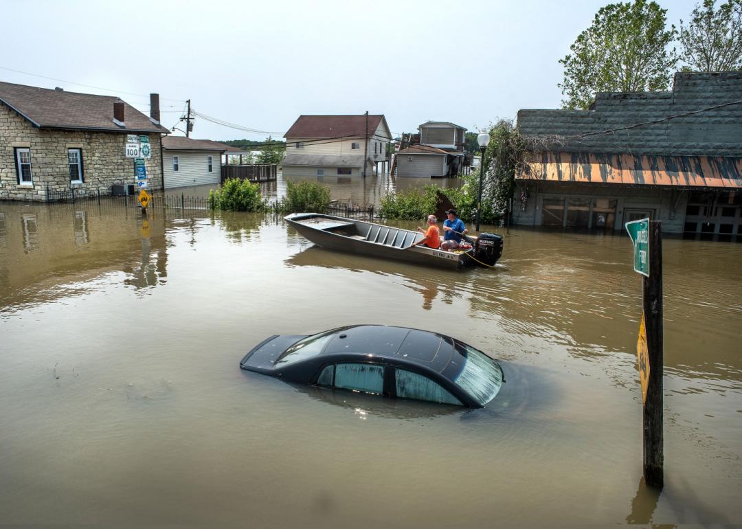 Residents riding in a boat pass a car submerged under flood water in small river town, Grafton, Illinois.