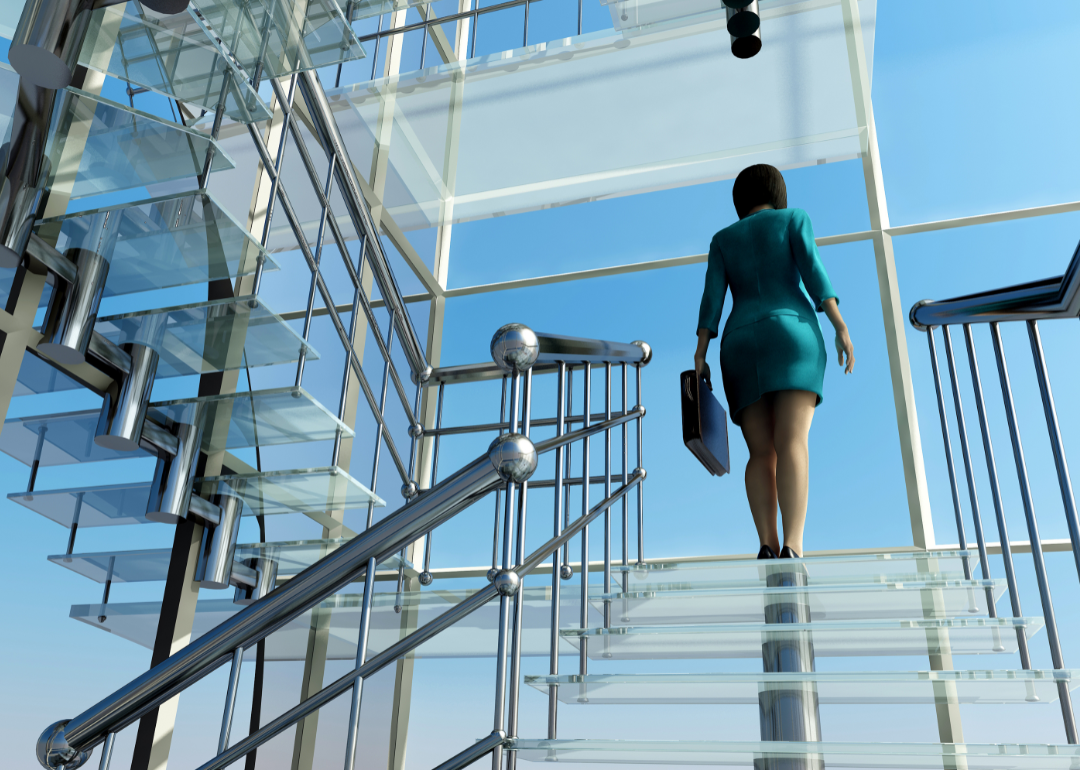 A woman ascends a staircase in a modern glass building.