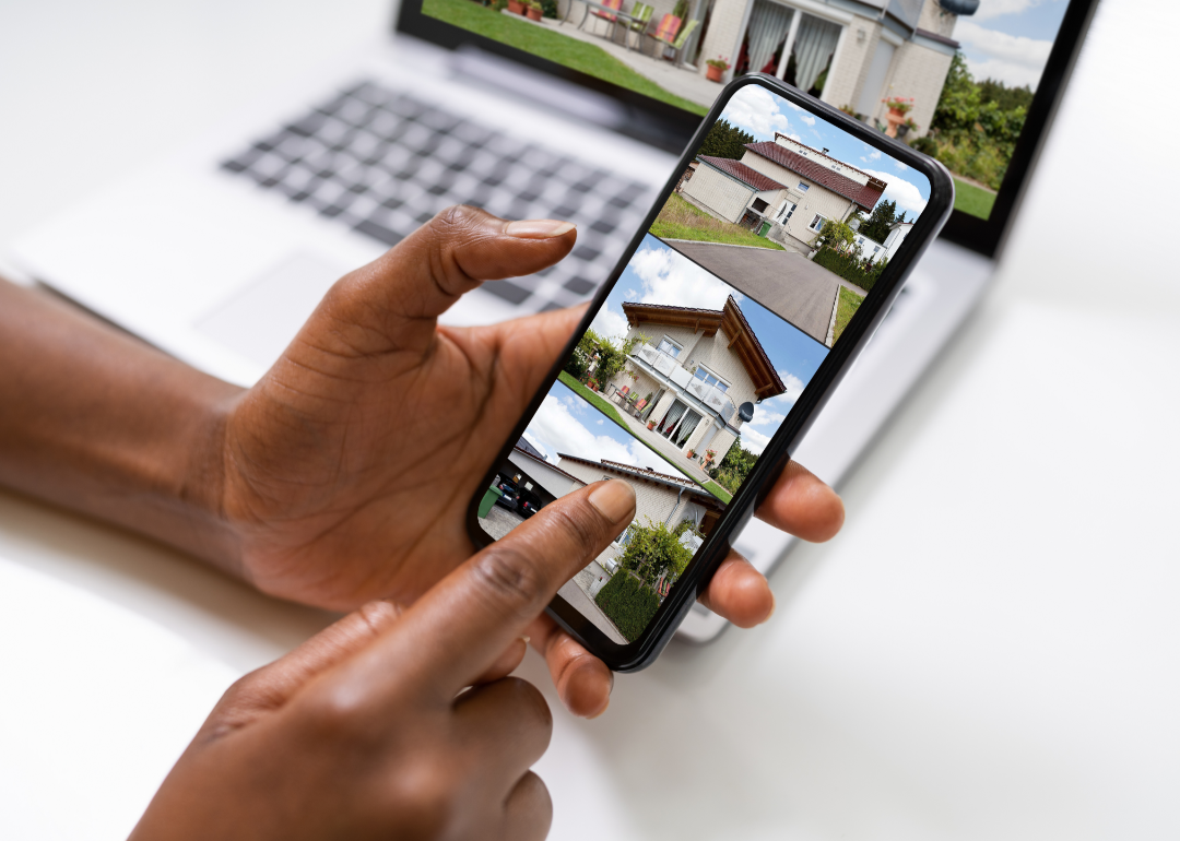 Two hands explore real estate options on a smart phone and a laptop.