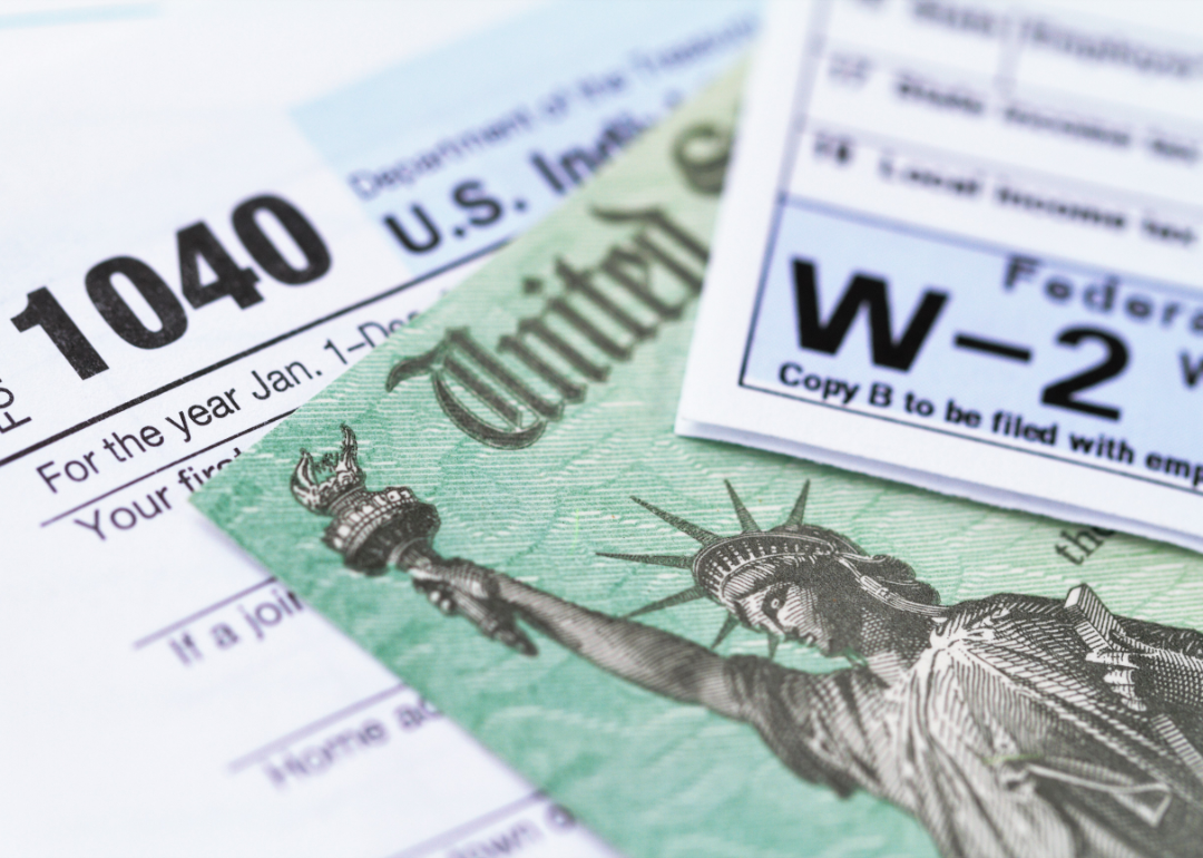 A 1040 tax form, a W-2 form and a tax refund check lie in a pile.