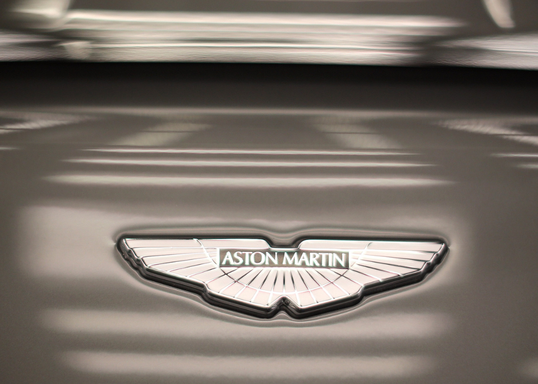 The Aston Martin logo on a silver metallic surface.