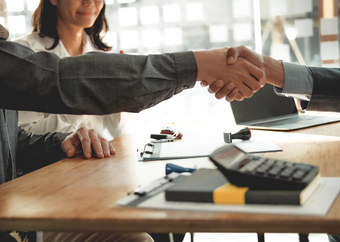 A handshake over a desk in an office setting.