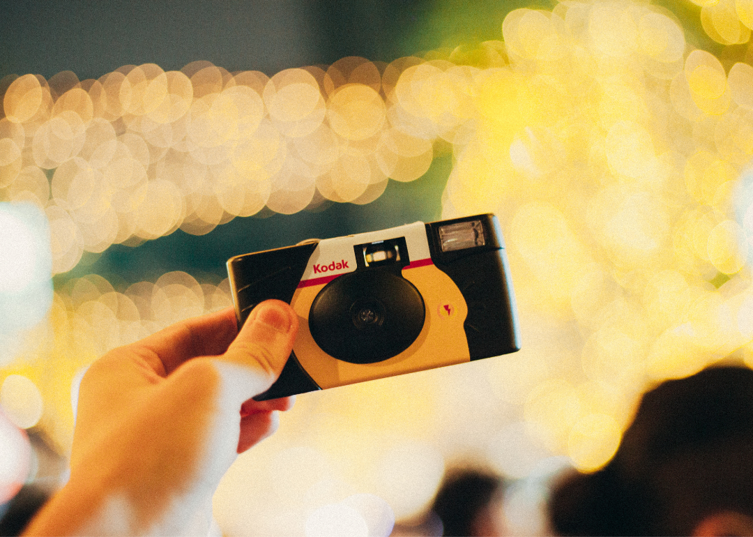 A hand holding up a disposable Kodak camera.