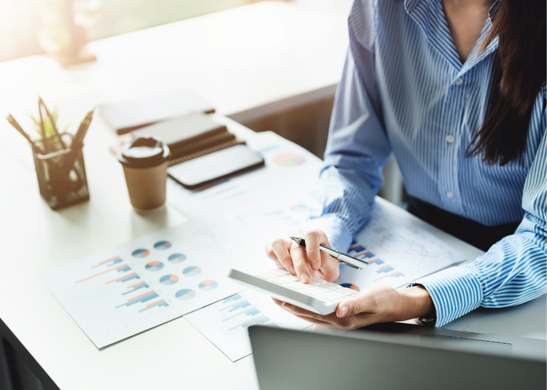 Woman sits at a desk reviewing financial charts.