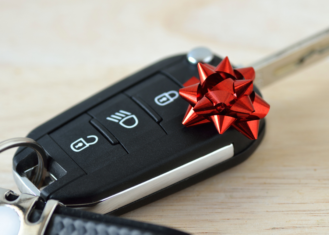 A car key fob with a red bow on it resting on a desk.