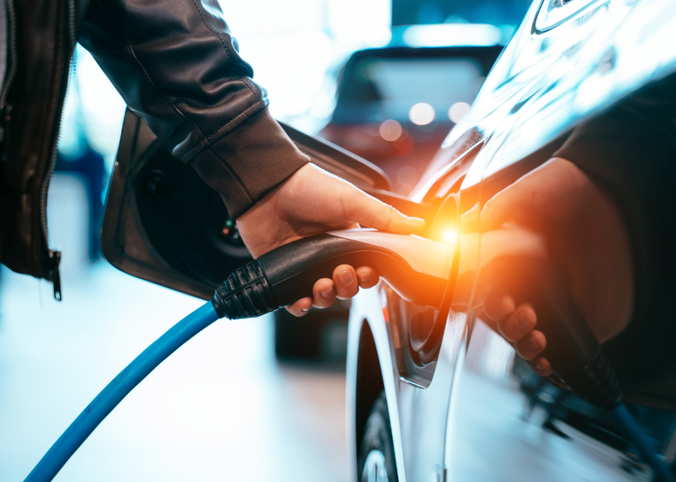 A person is placing an EV charge plug into the charge port of an electric car