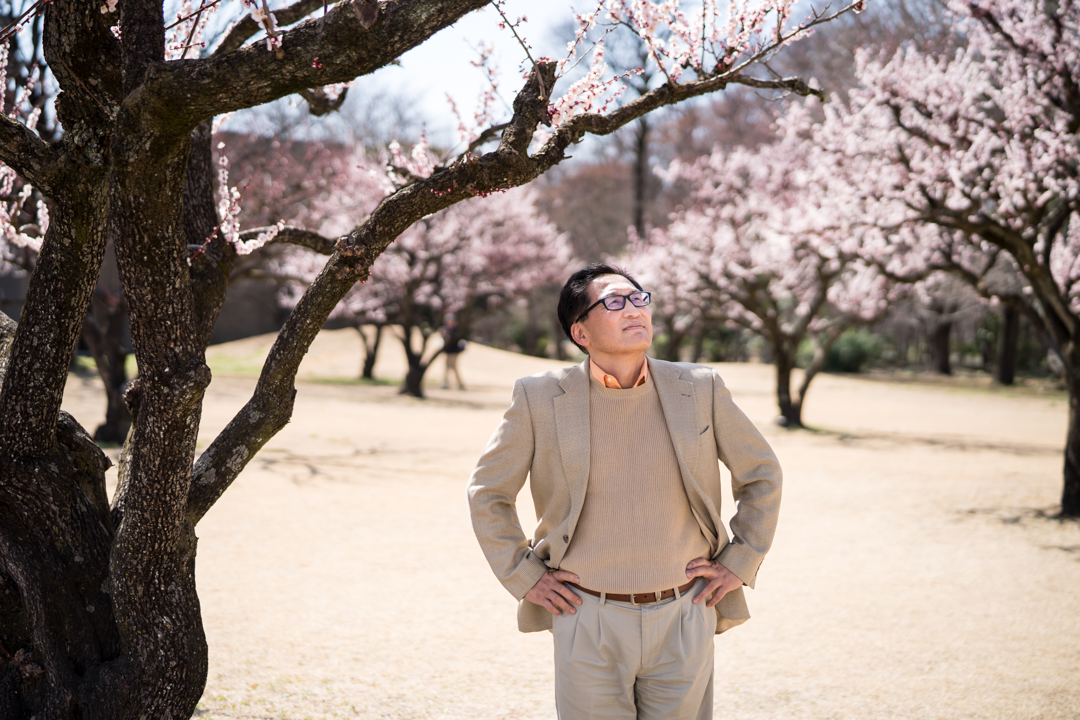 A man stands under flowering trees.