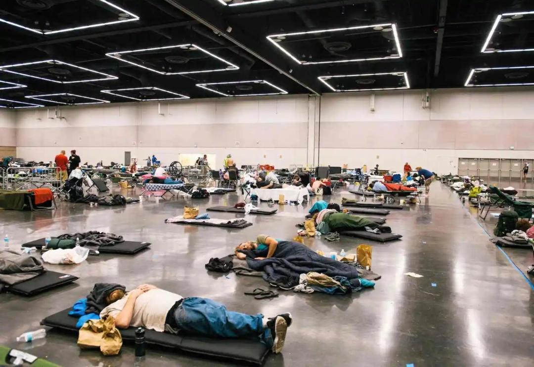 People lie on air mattresses on the floor in a large open room in Portland.