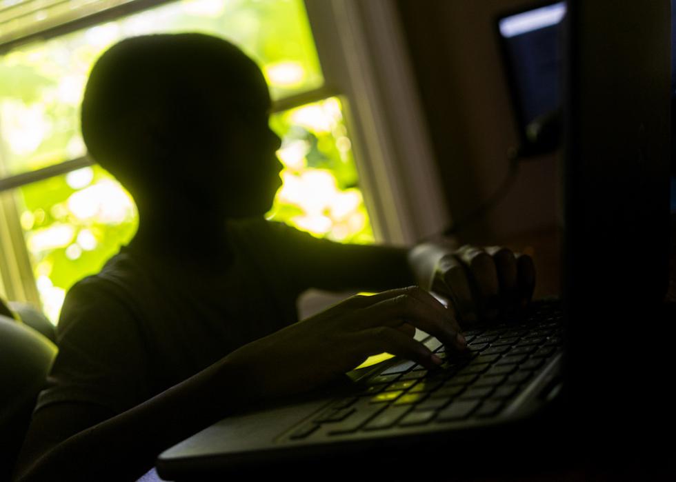 A young Black child sits at a computer terminal