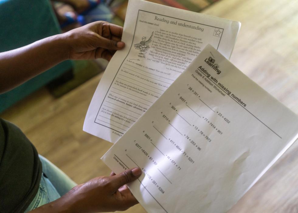 Rosalind Crawford holds two worksheets she printed off for her sons to supplement their education after all five were indefinitely sent home for virtual learning by their school district. 