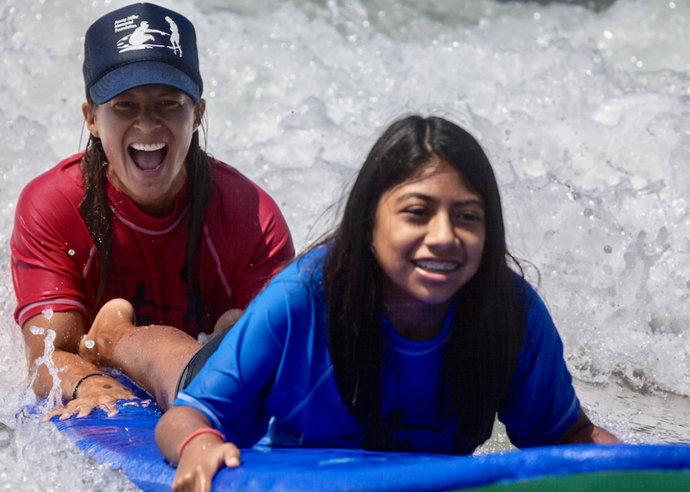Surfing therapist Kris Primacio helps a young girl on a body board