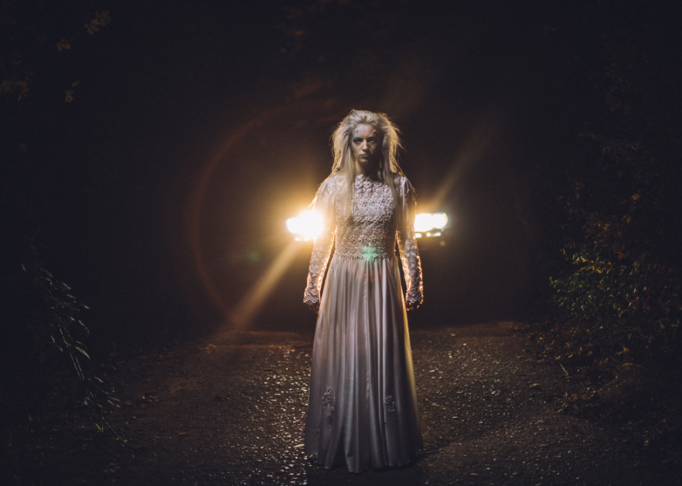 Blonde ghost standing in front of a car's headlights
