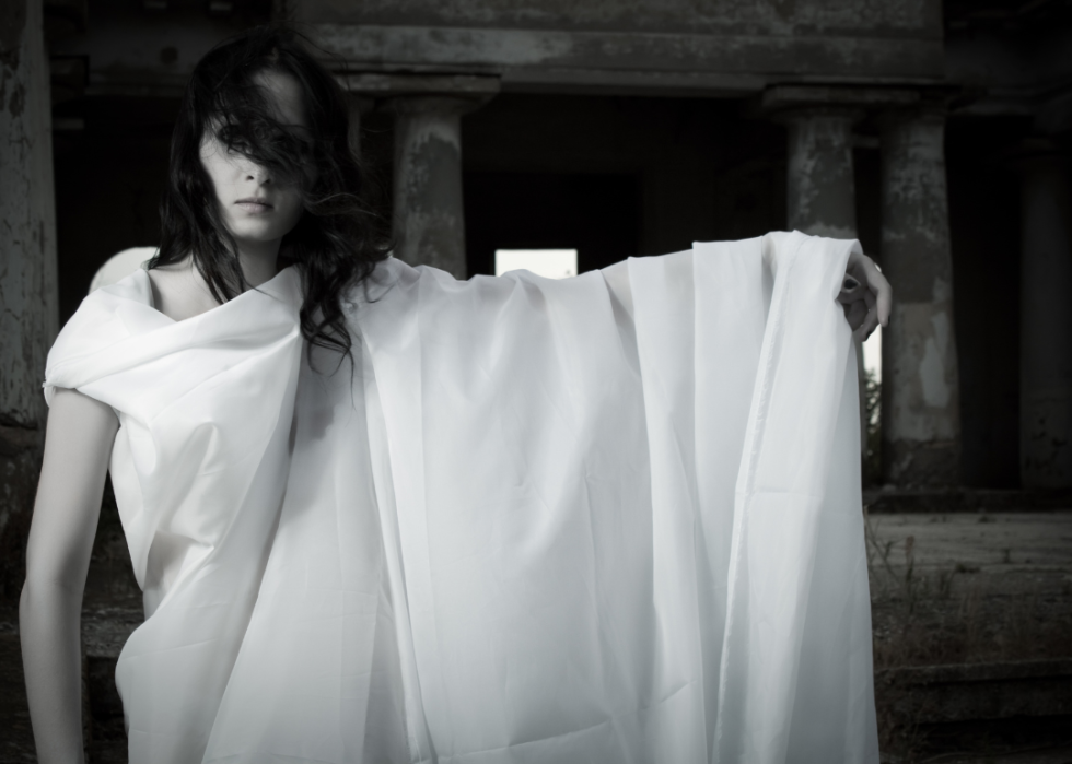 A young girl dressed as a ghost in white sheeting