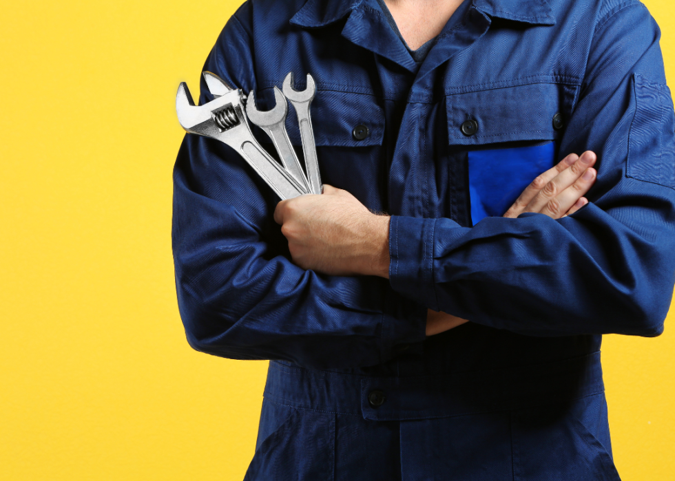 A mechanic holding three wrenches