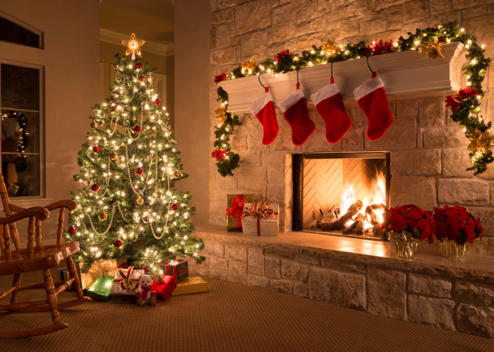 A Christmas tree in a home with a fireplace and stocking hanging above it
