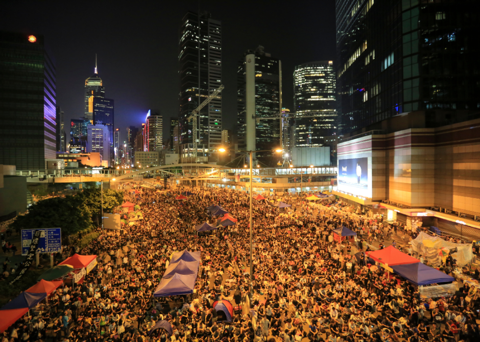 An elevated view of a city street crammed with protestors at night.