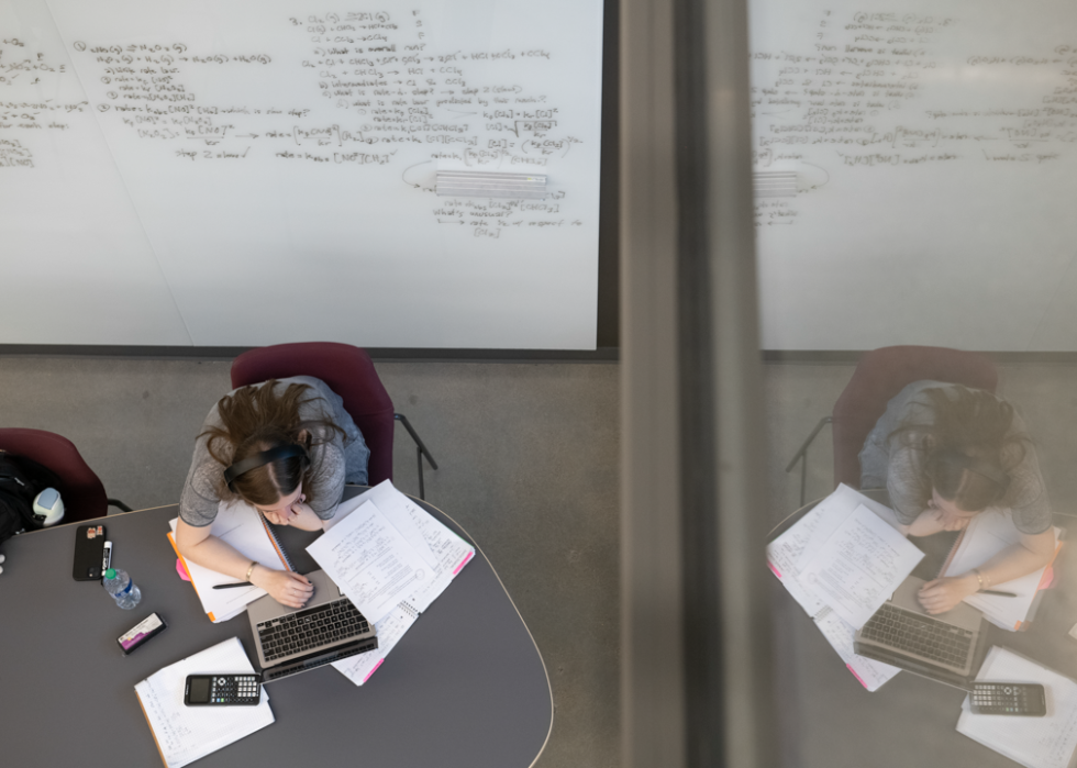 A student at Northeastern University is reflected in a window while studying. 