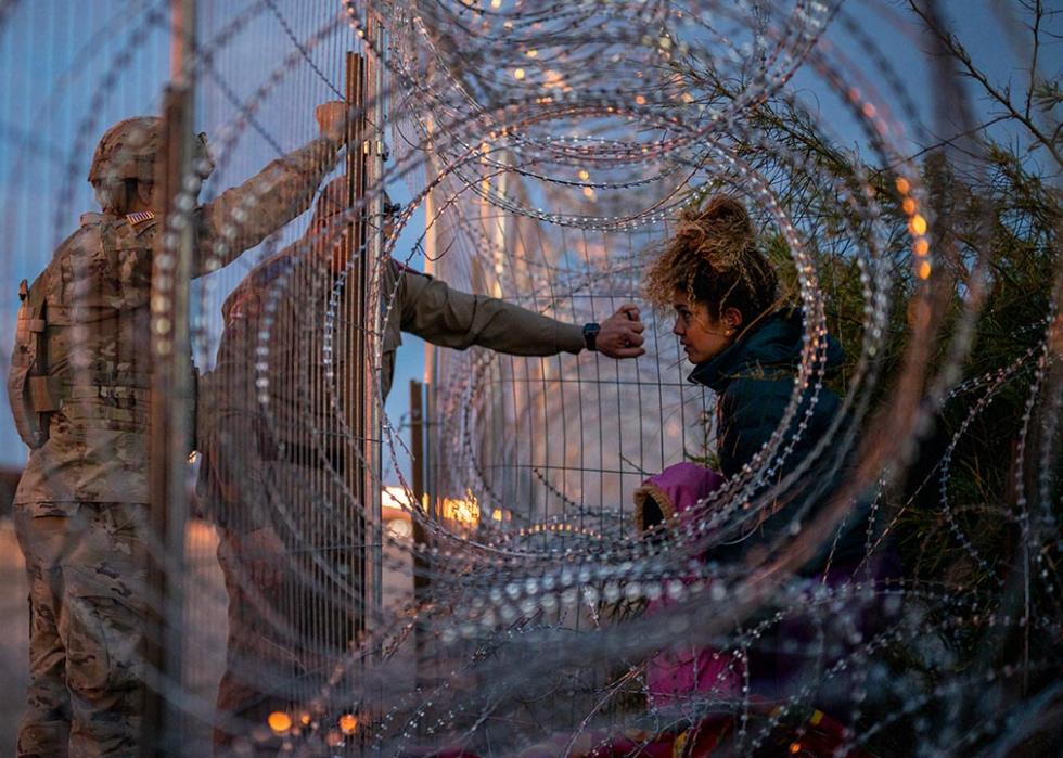 Photographed through concertina wire, Eliana, 22, a migrant from Venezuela, holds her daughter Crismarlees, 3, while being denied entry after attempting to cross through concertina from the U.S. side of the Rio Grande river on March 26, 2024 in El Paso, Texas. 